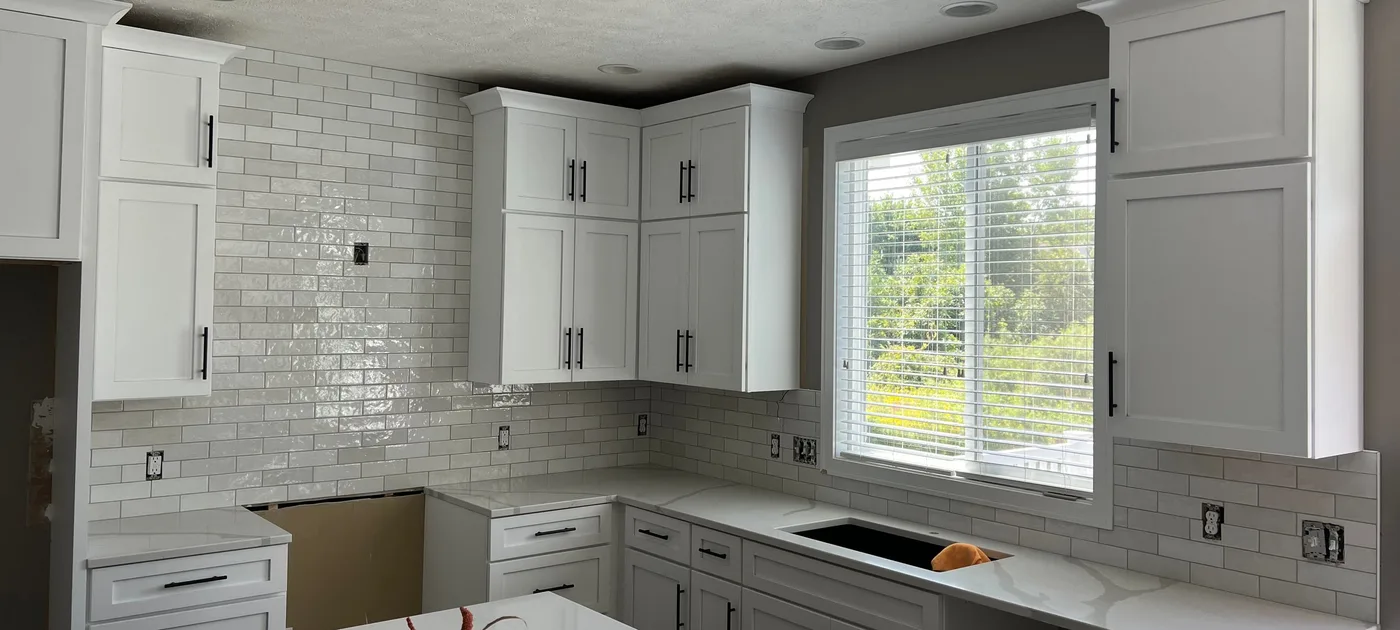 Kitchen with glossy white handmade-look subway tile running full height on one wall and as a backsplash around the window