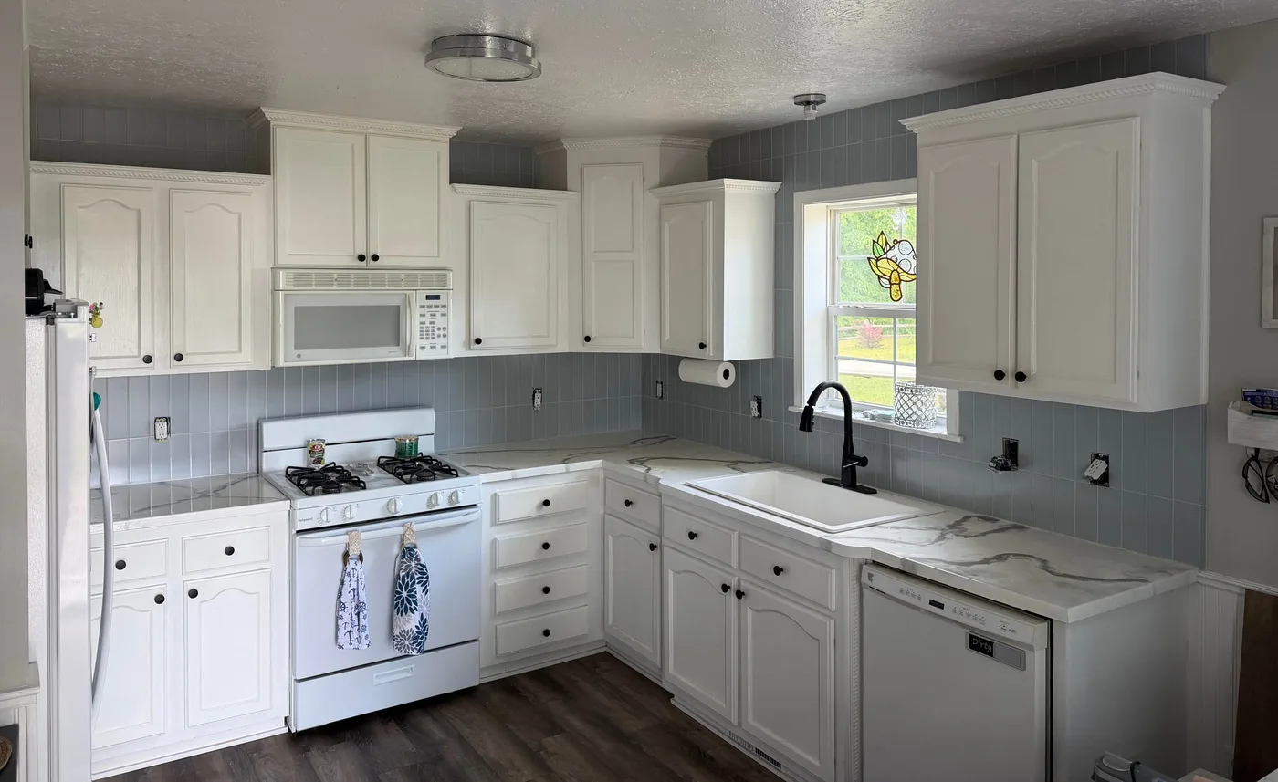 White kitchen with a soft gray tile backsplash laid in a vertical stack, running up to the ceiling above the cabinets