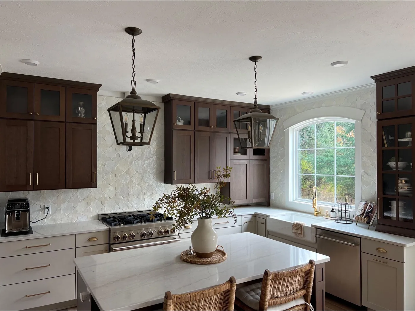 Kitchen with a full-height white star-and-cross ceramic tile backsplash running from the quartz counters to the ceiling, around an arched window, with dark stained cabinets and brass hardware